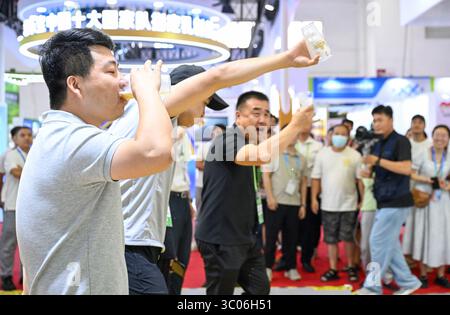 La gente beve birra allo stand di Tsingtao. Pechino, Cina. 19 luglio 2025. La terza China International Supply Chain Expo apre al pubblico a Pechino, 19 luglio 2025. Crediti: Zhao Wenyu/China News Service/Alamy Live News Foto Stock