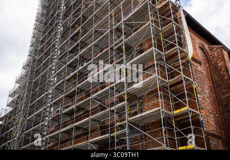 Ponteggi in metallo che coprono pareti in mattoni dell'edificio storico in fase di ristrutturazione Foto Stock
