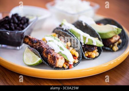 Tre Tacos di pesce con avocado e panna acida Foto Stock