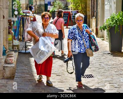 Due donne più anziane - una con fotocamera reflex digitale - con acquisti di articoli da regalo nel centro città - Loches, Indre-et-Loire (37), Francia. Foto Stock