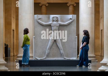 Londra, Regno Unito. 21 luglio 2025. Membri dello staff con «Primeval Gods» 1910, 1931-3, di Jacob Epstein in una nuova esposizione di opere dell'influente scultore britannico del XX secolo Jacob Epstein alla Tate Britain. Sculture monumentali in pietra e busti ritratti in bronzo sono in mostra nelle gallerie Duveen. Crediti: Stephen Chung / Alamy Live News Foto Stock