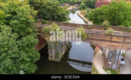Vista aerea del vecchio ponte in mattoni sulle tranquille acque del fiume Wey, incorniciato da una vegetazione lussureggiante, Guildford, Inghilterra, Regno Unito. Foto Stock