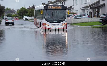 Un autobus passa attraverso le acque alluvionali della Bay Estate a Dundalk, Co Louth, mentre gli avvisi meteorologici di livello arancione erano in vigore per alcune parti dell'Irlanda dopo una notte di forti piogge attraverso l'isola. Data foto: Lunedì 21 luglio 2025. Foto Stock