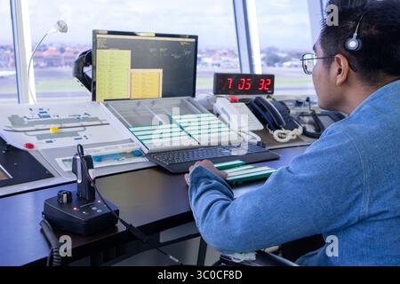Bali, 20 luglio 2025: Il controllore del traffico aereo monitora i dati degli aeromobili presso la torre di controllo dell'aeroporto durante il turno di mattina presto Foto Stock
