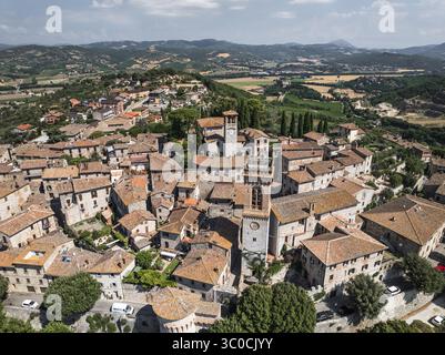 Veduta aerea dei tetti di terracotta che scendono lungo l'antico borgo, con i campanili iconici che perforano lo skyline, Corciano, Umbria, Italia. Foto Stock