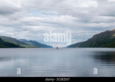 Barca a vela con vele rosse sul lago di Loch Ness, vista da Fort Augustus, Highland, Scozia Foto Stock