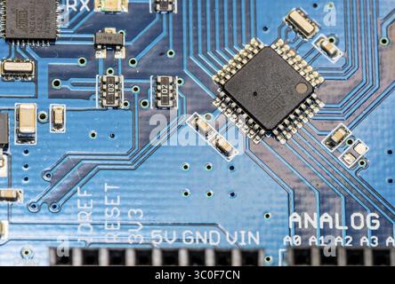 Vista dettagliata di un microchip su una scheda a circuito stampato blu con componenti elettronici Foto Stock