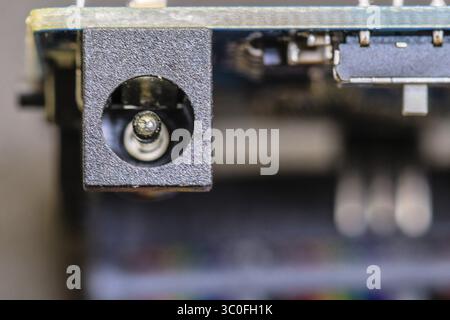 Primo piano di una porta del connettore di alimentazione su una scheda a circuito stampato, evidenziando il design elettronico Foto Stock