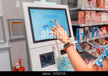 1 giugno 2025, Belgrado, Serbia: Donna che paga la spesa al check-out self-service in un supermercato DM, utilizzando un touchscreen e una carta di credito Foto Stock