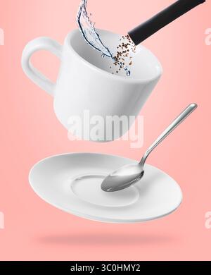 Preparazione del caffè istantaneo. Combinazione di granuli da bustina e acqua in tazza su sfondo rosa Foto Stock