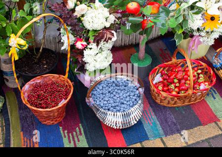 Tre cestini con frutti di bosco freschi e succosi sul mercato di strada. Sfondo frutti di bosco. Fragole, mirtilli, ribes rosso. Mercato in campagna. Foto Stock