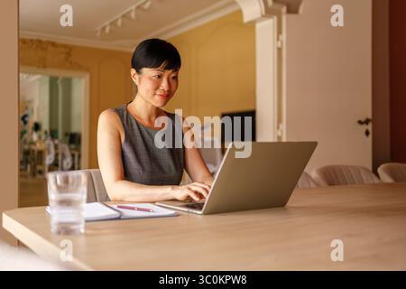 Ritratto di una donna d'affari in età adulta che lavora a un progetto su un computer portatile alla scrivania in un ufficio moderno Foto Stock