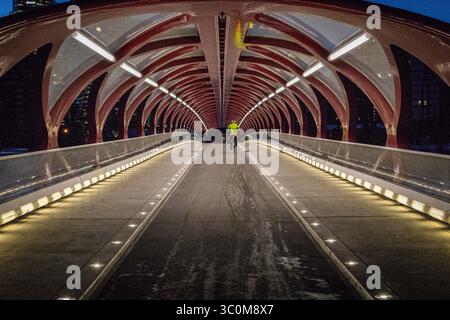 I ciclisti e i pedoni si spostano utilizzando il Calgary Peace Bridge, Calgary, Alberta, Canada Foto Stock