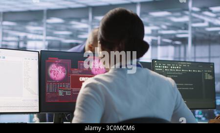 Donna che vede un errore critico sullo schermo del PC nel data center e chiede aiuto al team di sicurezza informatica. Dipendente che vede incidenti di sicurezza che interessano il sistema di rete della sala server, videocamera A. Foto Stock
