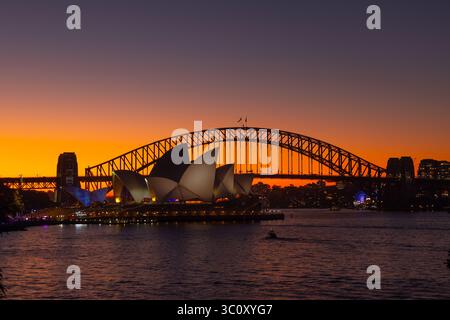 I tramonti sulla Sydney Opera House e sul Sydney Harbour Bridge, che si trovano sulla riva del porto di Sydney Foto Stock