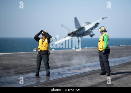29 dicembre 2018 - Golfo Arabico - Un marinaio dirige un aereo verso una catapulta a vapore come F/A-18F Super Hornet assegnato allo Strike Fighter Squadron (VFA) 41 lanci dal ponte di volo della portaerei USS John C. Stennis (CVN 74) nel Golfo Arabico, 29 dicembre 2018. Il John C. Stennis Carrier Strike Group è schierato nella zona delle operazioni della 5th Fleet a supporto delle operazioni navali per garantire la stabilità e la sicurezza marittima nella regione centrale, collegando il Mediterraneo e il Pacifico attraverso l'Oceano Indiano occidentale e tre punti strategici di strozzatura. (Credito IM Foto Stock