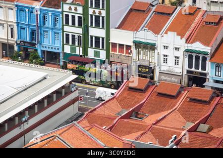 Vista aerea dei turisti sul Big Bus scoperto che visita Chinatown, Singapore. Cattura la vivace vita di strada, le attrazioni culturali e l'esperienza di viaggio urbana. Foto Stock