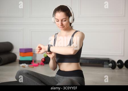 Donna che controlla il fitness tracker durante l'allenamento in casa Foto Stock