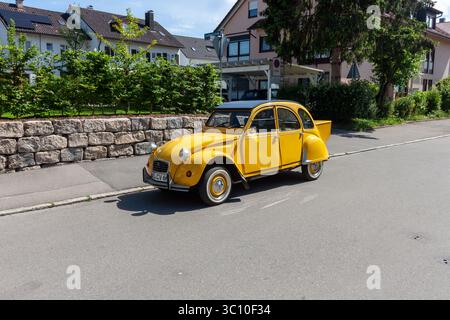 LINDAU, GERMANIA - 31 MAGGIO 2025: Un'auto d'epoca Citroën 2CV gialla, un'amata classica francese, è parcheggiata in una strada tranquilla in una giornata di sole Foto Stock