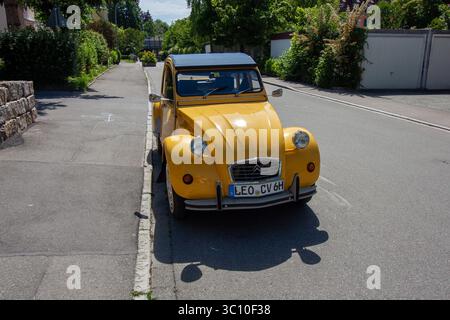 LINDAU, GERMANIA - 31 MAGGIO 2025: Un'auto d'epoca Citroën 2CV gialla, un'amata classica francese, è parcheggiata in una strada tranquilla in una giornata di sole Foto Stock