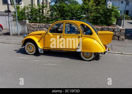 LINDAU, GERMANIA - 31 MAGGIO 2025: Un'auto d'epoca Citroën 2CV gialla, un'amata classica francese, è parcheggiata in una strada tranquilla in una giornata di sole Foto Stock