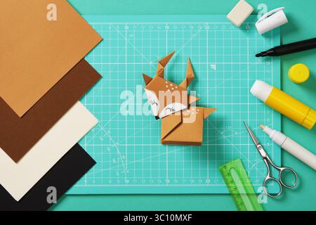 Cervo origami fatto a mano in carta marrone su un tavolo per l'artigianato della carta. Carta, righello, pennarelli, gomma, forbici, colla. Foto Stock