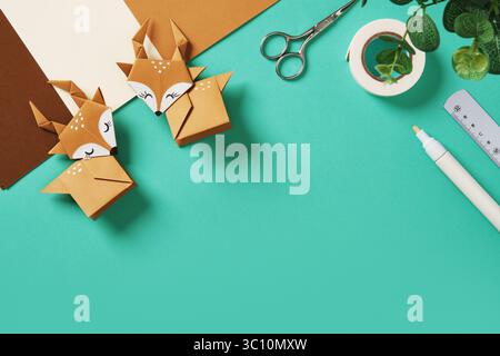 Due origami di carta marrone su fondo turchese. Elementi per arte cartacea, carta, righello, pennarelli e gomma. Spazio per il testo. Foto Stock