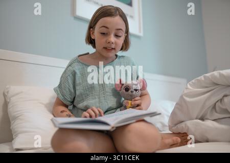 Il bambino legge in una camera da letto prima di andare a dormire. Foto Stock