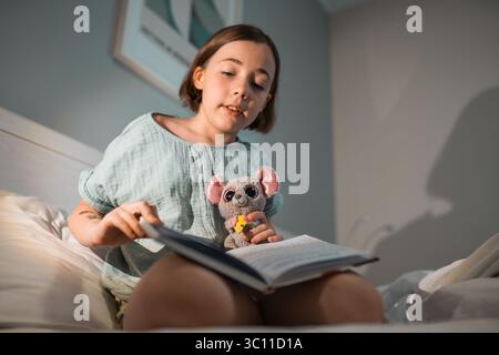 Il bambino legge in una camera da letto prima di andare a dormire. Foto Stock