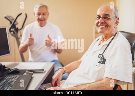 Felice paziente che ha un esame medico al cardiologo. Medico e paziente soddisfatti che guarda la fotocamera e sorride. Foto Stock