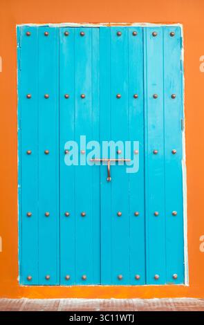 Porta e parete in legno dipinte di fresco in colori a contrasto blu (turchese) e terracotta. Nastro di mascheratura ancora presente Foto Stock