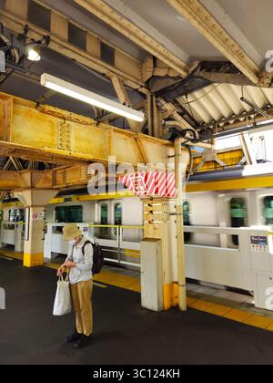 Stazione Tokyo Higashi-Nakano - trave arrugginita, linea Chuo-Sobu in movimento e Commuter in attesa Foto Stock