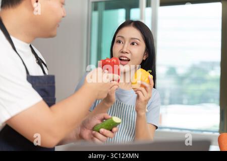 Divertimento in cucina: Amici che si godono i coloratissimi peperoni Bell in Bright Kitchen Foto Stock