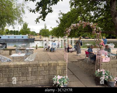 Luglio 2025 persone che gusteranno tè e torta fuori da un caffè, un negozio di tè, accanto al canale Kennet e Avon che attraversano Newbury, Berkshire Foto Stock