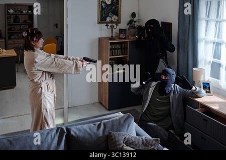 Donna che affronta gli intrusi mascherati durante Home Invasion Foto Stock