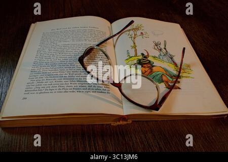 Un libro di fiabe d'epoca aperto su un tavolo, primo piano. Mostra i gamberi Maerchen con testo e un'illustrazione del Lupo e dei sette giovani capre. A. Foto Stock