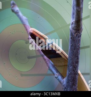 Un multilivello con un arco nella parte anteriore e un bersaglio con 3 frecce nel livello di sfondo. È un'immagine creativa. Foto Stock