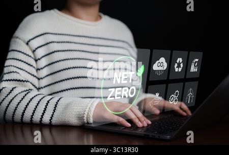 Donna che utilizza un computer portatile con icone Net Zero. Strategia a lungo termine neutra dal punto di vista climatico. Sostenibilità della decarbonizzazione, gas serra Foto Stock