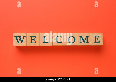 Parola di benvenuto: Cubi di legno su sfondo rosso, vista dall'alto Foto Stock
