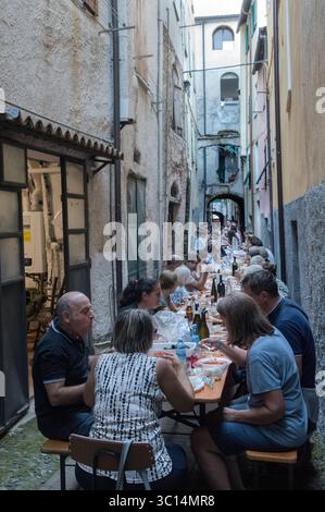 Borgomaro, un villaggio medievale italiano di montagna, organizza il suo festival annuale di conchiglie e cozze. I tavoli riempiono una stretta strada laterale, i residenti locali e gli amici si godono un pasto comune. Borgomaro, regione Liguria, Italia, Europa. Luglio 2025 HOMER SYKES Foto Stock