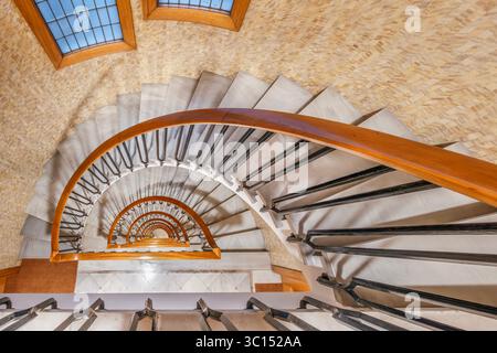 Vista astratta della scala a spirale dall'alto, elegante design architettonico. Ripetizione, forme geometriche, prospettiva interna Foto Stock