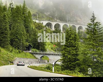 Veduta della strada frontale di Albula Veja Alvra dal passo di Albula verso Berguen con viadotto per la ferrovia di fronte ad Albulaviadukt i 1, sopra la linea ferroviaria per tunne Foto Stock