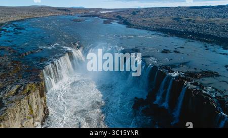 La cascata Selfoss si riversa drammaticamente nel fiume sottostante, circondato da terreni accidentati e formazioni geologiche uniche in Islanda. La vista mozzafiato cattura l'essenza della bellezza naturale. Foto Stock