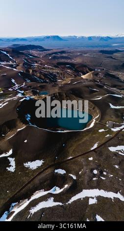 Il suggestivo cratere di Krafla rivela uno splendido lago turchese circondato da terreni accidentati e residui di neve. Questo luogo affascinante mette in mostra le meraviglie geologiche dell'Islanda all'alba. Foto Stock