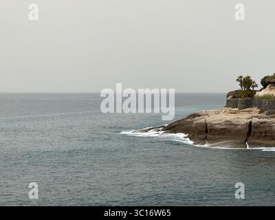 Vista panoramica costiera delle onde oceaniche che si infrangono contro una scogliera rocciosa sull'isola di Tenerife, una delle isole Canarie Foto Stock