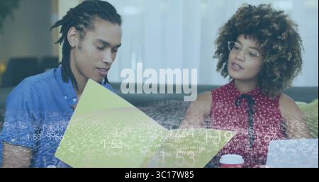 I colleghi che esaminano la cartella gialla sul divano grigio nella sala dell'ufficio, con un computer portatile color argento e una tazza da caffè Foto Stock