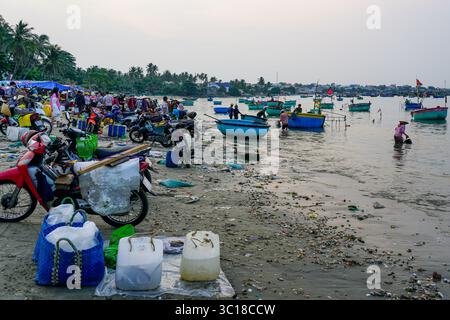 MUI ne, Vietnam - 22 marzo 2025: I pescatori tornano a riva con il loro pescato mentre la gente del posto si riunisce al vivace mercato del pesce mattutino di Mui ne in riva al mare Foto Stock