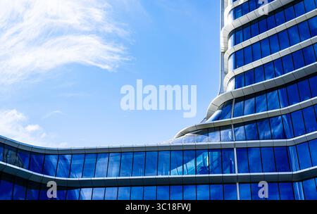 Moderno edificio residenziale a più piani con facciata vivace, grandi balconi e skyline urbano sotto il cielo azzurro Foto Stock