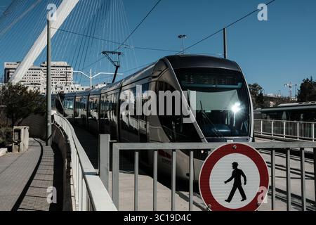 4 febbraio 2019 - Gerusalemme, Israele - Un tram sulla linea rossa di Gerusalemme scende dal ponte degli accordi di Calatrava. Il Jerusalem District Planning and Building Committee ha dato il via libera al nuovo percorso della ferrovia leggera, la linea blu, concludendo tre anni di deliberazioni sul suo percorso esatto. Nonostante questa decisione, la Construcciones y Auxiliar de Ferrocarriles, CAF, una società spagnola di costruzione di ferrovie, ha annunciato di aver respinto una gara d'appalto israeliana per partecipare alla costruzione della nuova linea tranviaria di Gerusalemme a causa dell'œthe occupazione â terra attraverso la quale passerà una sezione della ferrovia. Foto Stock