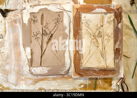 Rilievo in gesso botanico finito e stampo in argilla affiancati. Opere d'arte floreale fai da te in una cornice in legno che mostra dettagli di fiori e foglie, resu Foto Stock